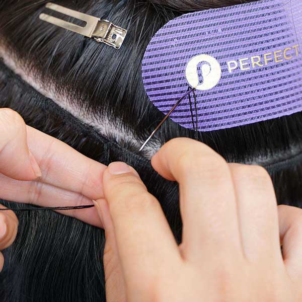 stylist sewing in wefted hair